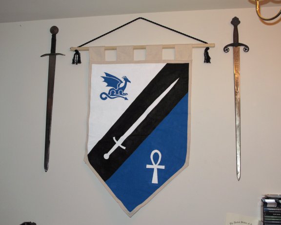 My custom banner, made by <A href="http://www.dirkandarrow.com/">Dirk & Arrow</A>. It sits between my first two swords that I collected. The first one (on the right) was just a $20 wall-hanger that falls apart when I mess with it. I was about 13 and finding it for sale at such a price in an antique shop was like hitting the jackpot. The second sword (on the left) was the only time in my youth that I ever saved up for something all summer long. I bought it from Baltimore Knife and Sword at MDRF, and I was probably about 15 or 16 at the time.