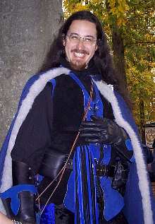 Here I am grinning in a silly manner. I'm wearing my fullgarb in this shot again, but this time with the brand-newcrushed velvet tights (I never ever thought I would weartights, but I've been talked into it). Also, you can see the new "Cat O' Ninety Tails" whip I had stuck on my belt. 'Twas a gift, and it matched perfectly.. Muahahah!! (actually, it was a gag-gift, since a friend ofmine and I were talking and both agreed that we'd neverhit someone.. However, it turned out to be a good additionto the outfit, since now I have a "weapon" that I can carryeven at the faires that don't allow weapons)</I>