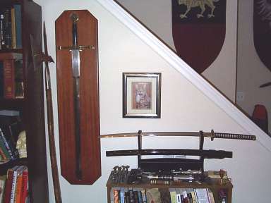 My bookcases are decorated with a few nice pieces here, includingmy Art Gladius Excalibur, Shinto Katana, and english-stylehalberd. On the small bookcase, there is also a light-saber. :) (Click for larger view)