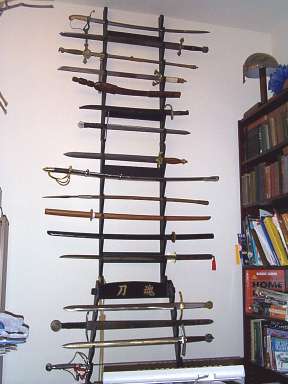 Here you can see the top of the floor-rack, plus the two wall-racksabove it, going all the way to the cieling. These two wall rackshold 14 total, though in this shot I have a zulu short-spear andtwo bokken as place-holders, and another slot free. (Click for larger view)